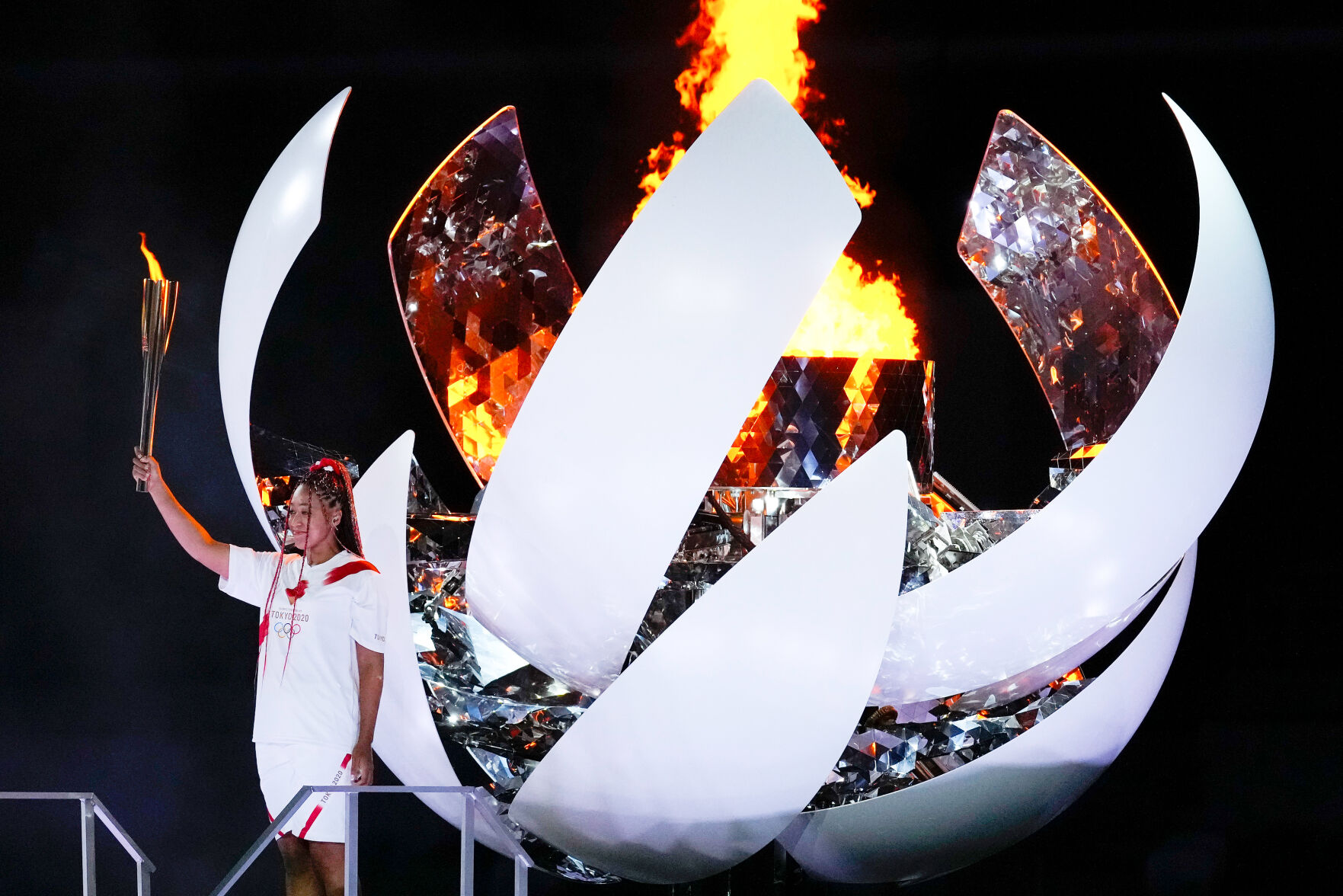 Naomi Osaka stands beside the Olympic flame